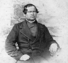 Portret księdza J. Stolarczyka siedzącego.