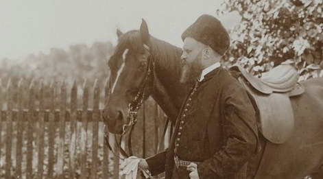  Karol Lanckoroński w stroju narodowym trzymający za wodze konia.  