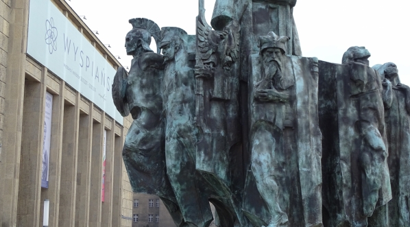  Fragment pomnika Stanisława Wyspiańskiego w Krakowie z widocznym w tle gmachem Muzeum Narodowego i banerem wystawy "Wyspiański".  